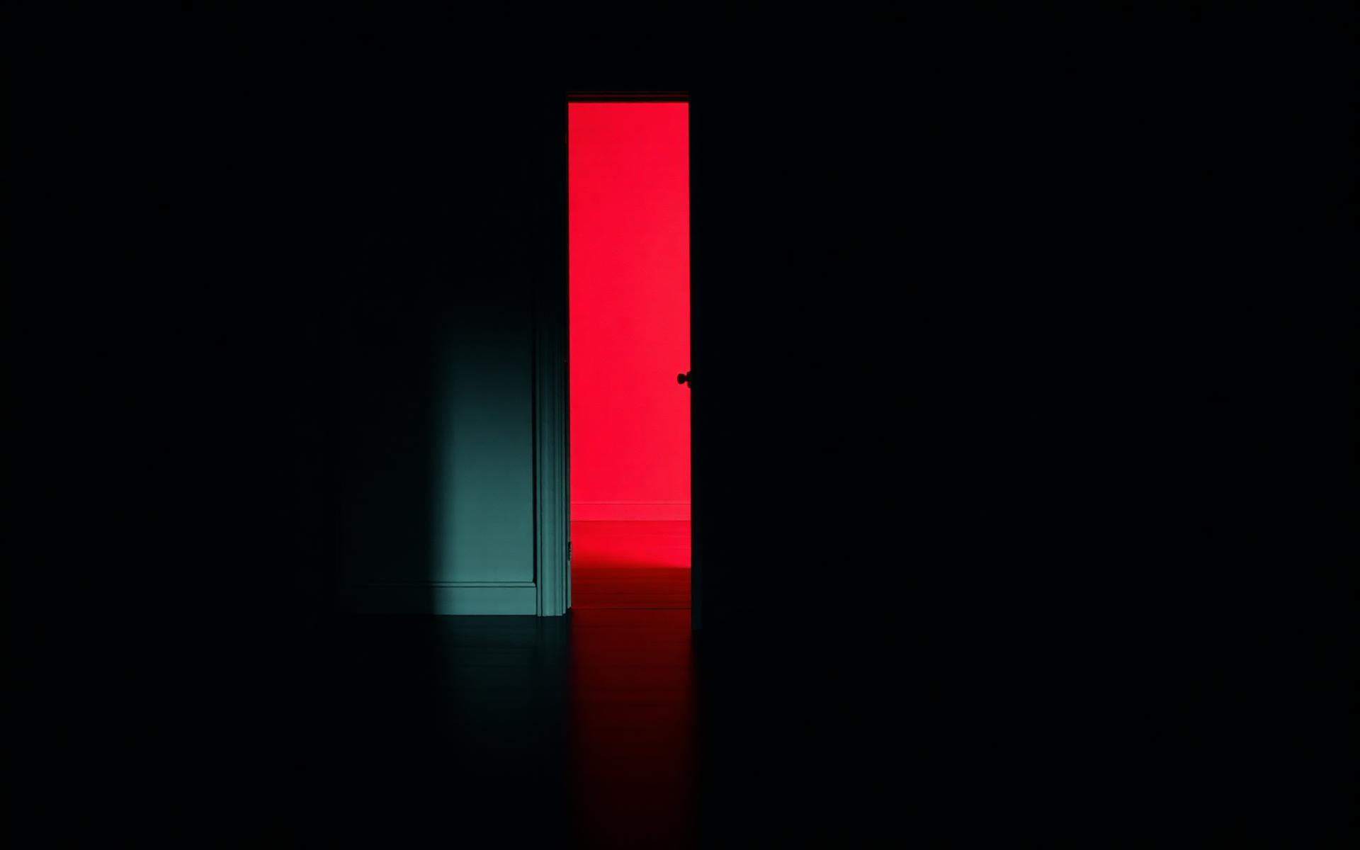 A dim hallway with a doorway spilling deep red light onto the floor